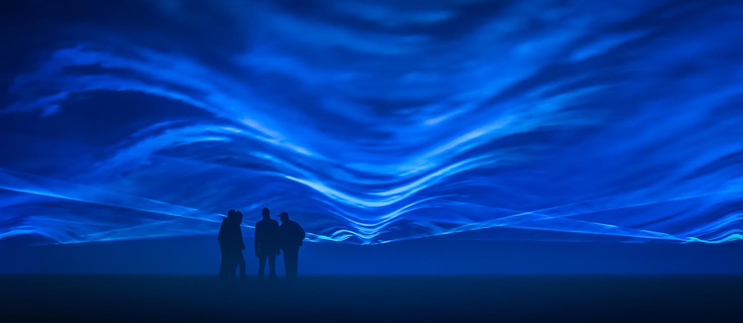 Blue waves of light with shadows of four people standing in the foreground.