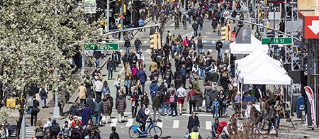 A large group of pedestrians stroll through the car-free intersection of Broadway and West 18th Street in Manhattan.