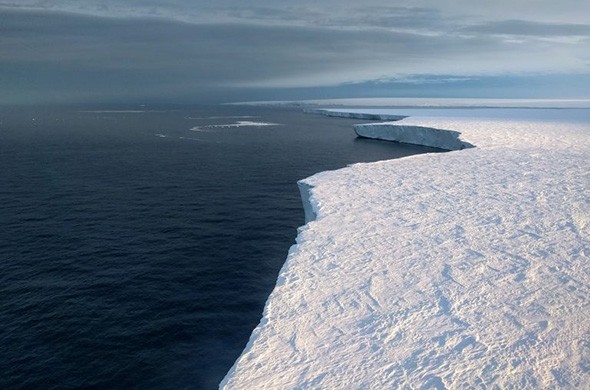 An ocean meets a wall of ice, tapering off into the distance.