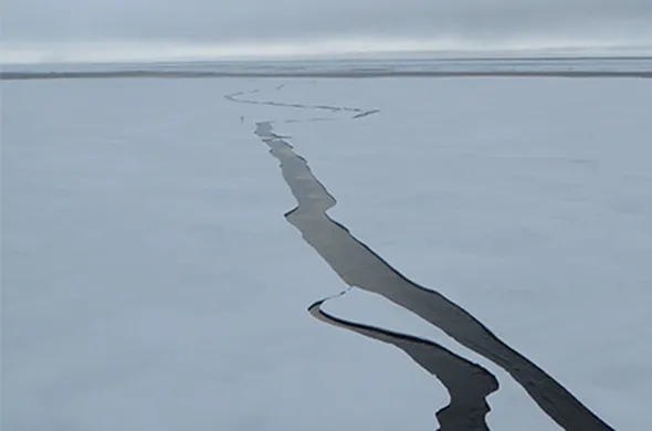 A rivulet of melted water runs through a frozen ice sheet far into the distance (oceanservice.noaa.gov/facts).