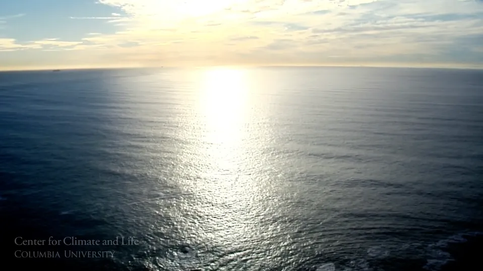 Clouds and setting sun on horizon over blue body of water
