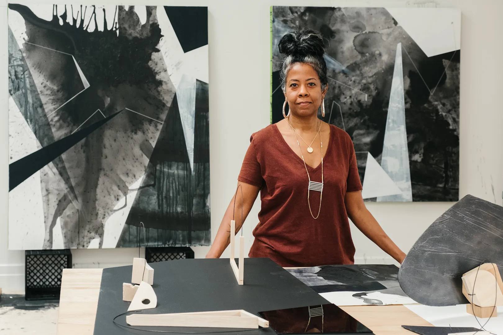 Woman with dark hair standing in front of her black and white paintings