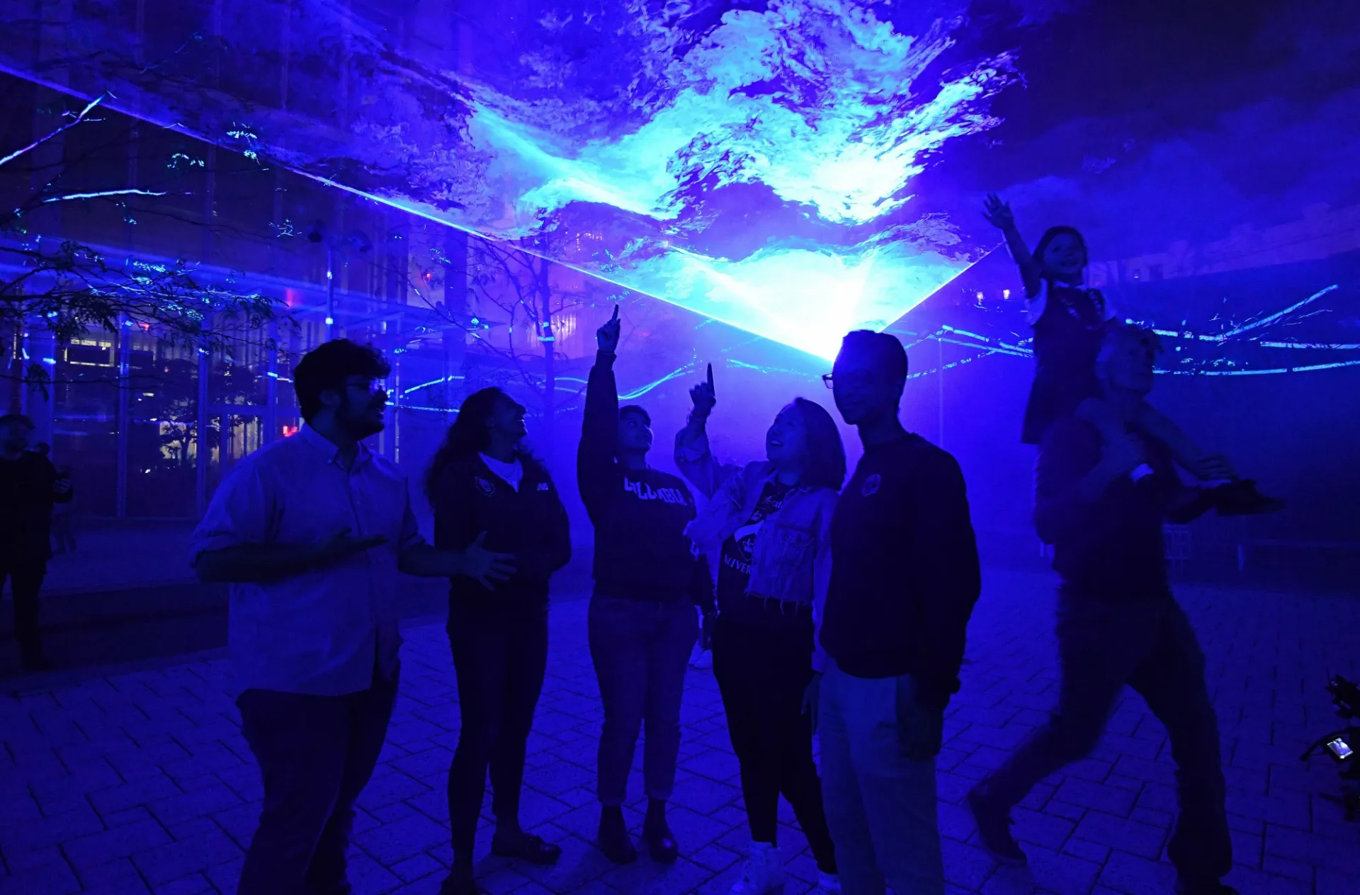People in the dark looking up at blue light.