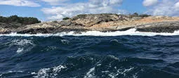 Choppy ocean waves hitting against a rock formation.