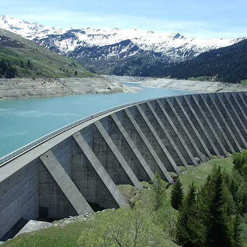 In a mountain gorge, a dam/bridge holds back an ice-blue river. Copyright ciboulette; image courtesy of goodfreephotos.com
